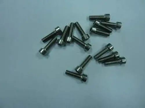 Mehrere Metall-Schrauben liegen auf einer grauen Oberfläche. Die Schrauben sind von der Marke Remeha und haben eine zylindrische Form mit einem flachen Kopf.
